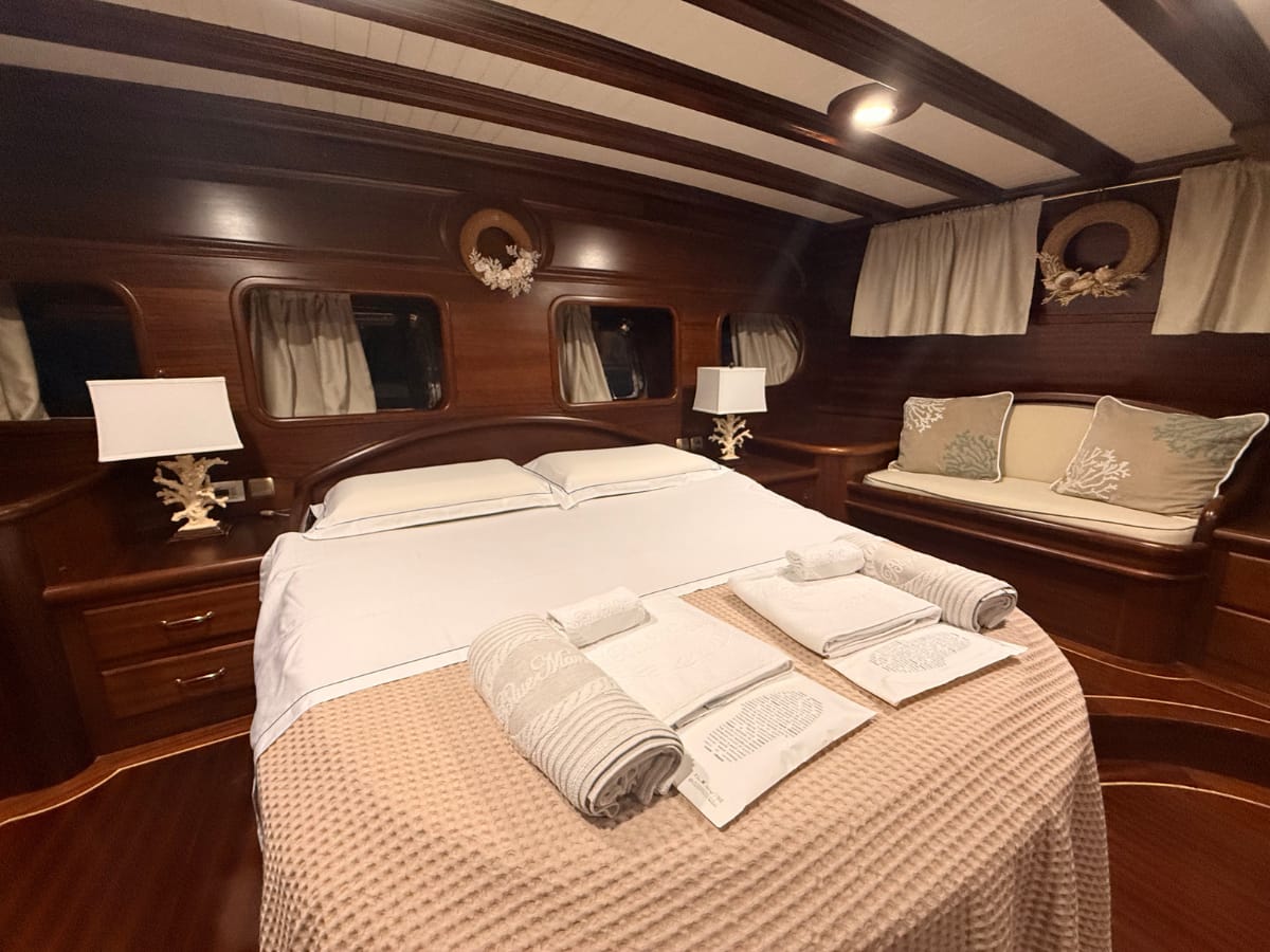Ingresso cabina armatoriale. ampio letto con accesso laterale, divanetto con cuscini, grandi oblò di poppa, comodini e abat-jour in corallo, armadi e ghirlande di conchiglie