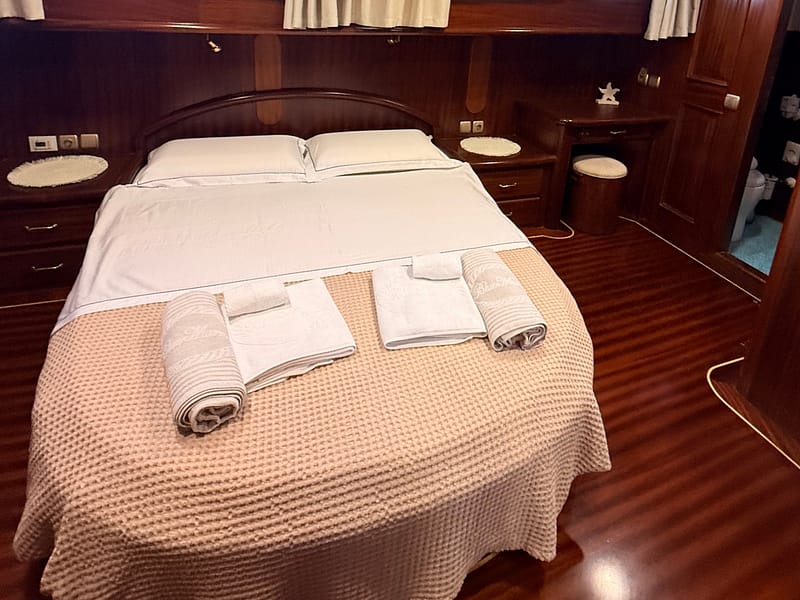 Letto matrimoniale in cabina in caicco con lenzuola e asciugamani personalizzati