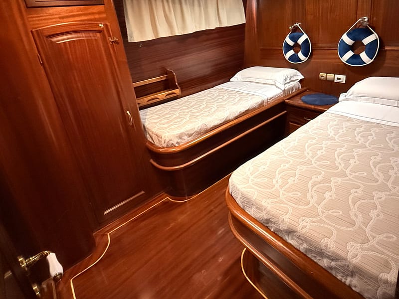 Letti del caicco silver star all'interno di una cabina interamente in legno finemente rifinito con lenzuola e copriletti di alta qualità