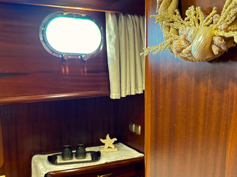 dettagli decorativi della cabina matrimoniale a bordo del caicco silver star 2: ghirlanda decorativa con conchiglie, vassoio con bicchieri e decorazioni in pietra arenaria, oblò